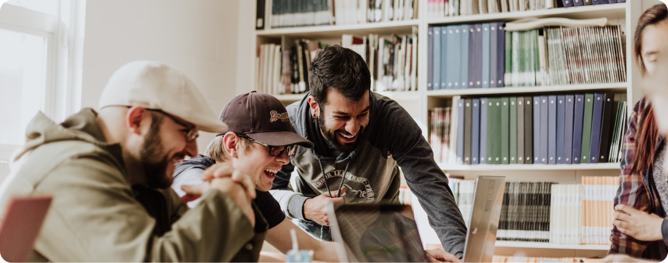 grupo de três homens sorrindo olhando para um notebook